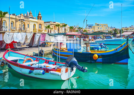 Il pittoresco villaggio di pescatori è uno dei più famosi luoghi turistici, attraendo con luzzu tradizionali barche nel porto, Marsaxlokk, Malta. Foto Stock