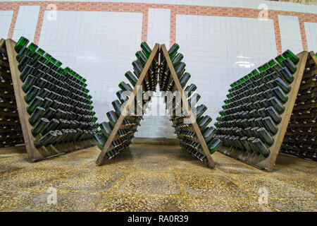 Sala di deposito bianco di bottiglie di vino spumante nelle Cantine della cantina vino spumante la fermentazione su cavalletti Foto Stock