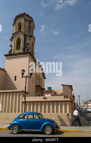 Una vecchia chiesa, un uomo a piedi e un vecchio blu VW Beetle, in Oaxaca, Messico Foto Stock