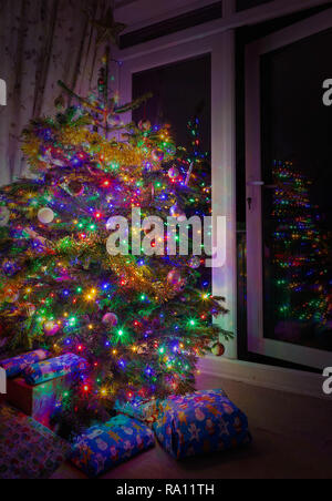 I regali di Natale sotto un albero con le luci fairy Foto Stock