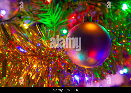 Baubel appeso a un albero di Natale con fata luce e tinsel Foto Stock