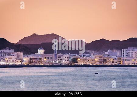 Paesaggio urbano in vista della città di Muscat al tramonto dorato. Il capitale di Oman. Foto Stock