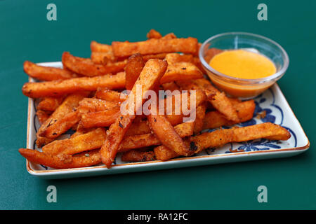 Porzione di deep dolce fritto patatine o patate fritte con salsa di immersione sulla piastra sopra il tavolo, ad alto angolo di visione Foto Stock