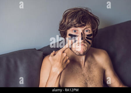 Uomo felice con maschera nera sul volto. Foto uomo ricevere trattamenti spa. La bellezza della pelle il concetto di cura Foto Stock