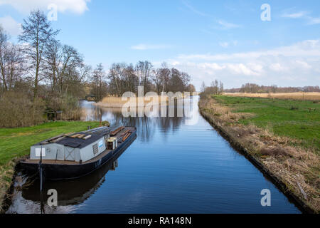 Inizio della primavera vista su Giethoorn, Paesi Bassi, un tradizionale villaggio olandese con canali. Una tipica barca bassa lungo il prato in un fosso. Foto Stock