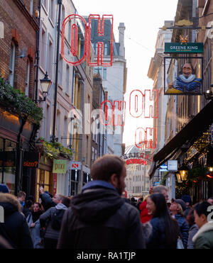 Gli amanti dello shopping a Carnaby Street, Soho, Londra sotto Natale luce al neon con l'installazione. Dicembre 2018 Foto Stock