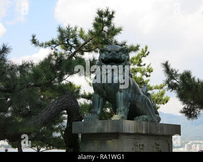 Close-up della bocca aperta lion (agyoo), uno della coppia di statue custodendo l'entrata al santuario di Itsukushima, l'isola di Miyajima, Giappone Foto Stock