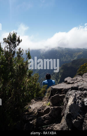 Escursionista solitario seduto su un colle roccioso con nebbia Foto Stock