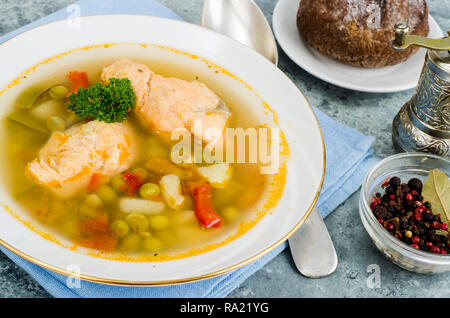 Zuppa di pesce con verdure e salmone in piastra bianca su sfondo grigio. Foto Studio Foto Stock