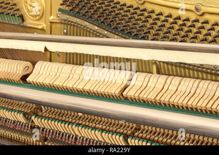 Una vista ravvicinata del meccanico di un pianoforte verticale, con la sintonizzazione i perni di attacco, teste di martello, la vibrante stringhe e la soft mute (sordino) panno di feltro Foto Stock