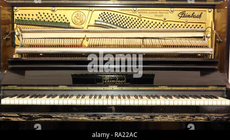 Completare la meccanica di un vecchio Steinbach pianoforte verticale che mostra la piastra con la sintonizzazione i perni di attacco, stringhe, martelli e leve, e aperto il coperchio della tastiera Foto Stock