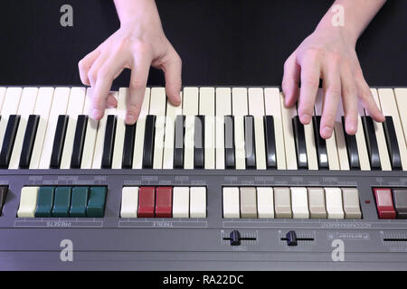 Una mano destra giocando a E (MI) principali corda su un vecchio nero pianoforte con ingiallito Tasti rotti, premendo il tasto E (MI), G# sharp (SOL#), B (SI) note Foto Stock