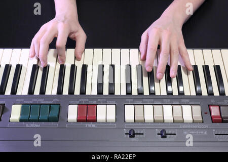 Una mano destra giocando una G (SOL) principali corda su un vecchio nero pianoforte con ingiallito Tasti rotti, premendo il tasto G (SOL), B (SI), D (RI) note Foto Stock