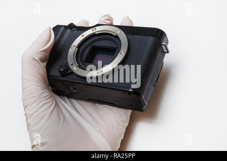 Close-up di mirrorless digital APS-C telecamera sporca sensore a matrice per la pulizia e la manutenzione con tampone, fotografo fotocamera di pulizia su bianco backgro Foto Stock