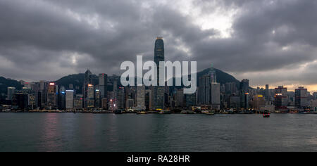 Le luccicanti torri dell'isola di Hong Kong dominano lo skyline come il sole comincia a impostare su Green Island in occidente. Foto Stock