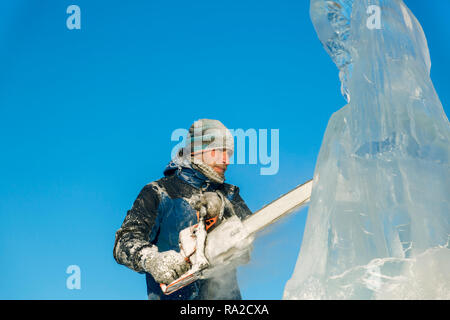 Lo scultore taglia il ghiaccio la figura di Santa Claus per Natale da una motosega ice Foto Stock