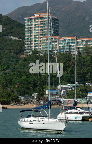 Discovery Bay contrasti: baracche di stagno la linea della spiaggia, costosi yacht ormeggiati nella baia, e appartamenti di lusso a comando la collina Foto Stock