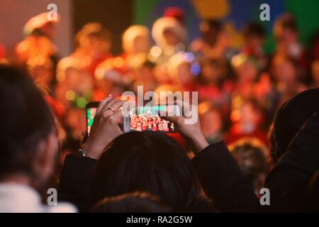 Registrazione genitore i loro figli durante una Natività giocare al tempo di Natale in una delle scuole primarie in Glasgow. Foto Stock