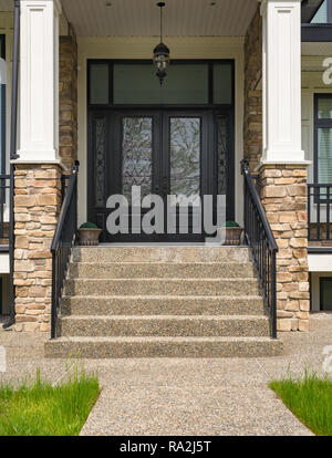 Ingresso principale della casa residenziale con sportello passi e vasi di fiori alla porta Foto Stock