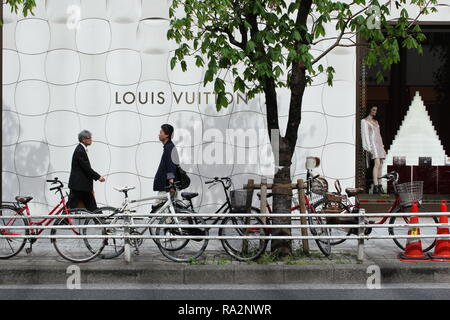 I pedoni a camminare al fianco di un grande negozio Louis Vuitton a Ginza con un distintivo Jun Aoki progettato facciata metallico. Foto Stock