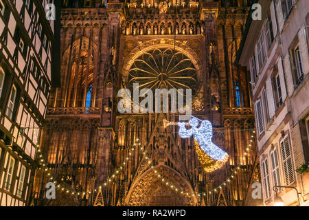 Illuminata la facciata anteriore della cattedrale di Strasburgo e il rosone con decorazione di Natale in primo piano, Alsazia, Francia. Foto Stock