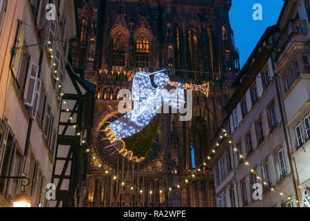 Illumina le decorazioni di Natale che rappresenta un angelo appeso di fronte alla strada nel centro cittadino di Strasburgo con la cattedrale in background, Francia. Foto Stock