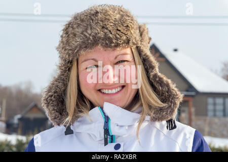 Donna sorridente indossando Cappello invernale in una fredda giornata invernale Foto Stock