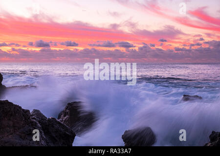 Tenerife, Isole Canarie, Spagna. 31 Dic, 2018. Red Sky e di onde che si infrangono sulle rocce della costa occidentale di Tenerife all'alba dell'ultimo giorno dell'anno. Foto Stock