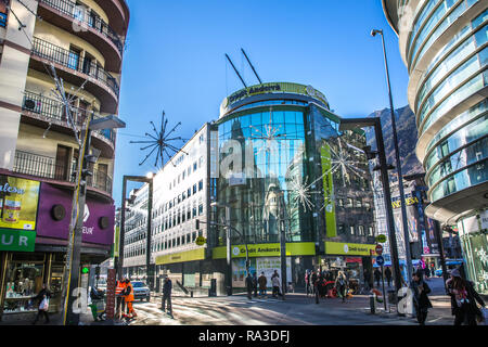 Andorra La Vieja, Andorra - 5 Novembre 2017 - un grande gruppo di persone che camminano in una strada con edifici riflettente e montagna in background nel Principato di Andorra Foto Stock