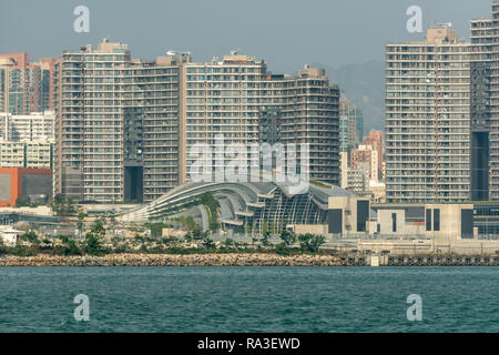 Le linee di spazzamento del tetto del nuovo West Kowloon Station in Hong Kong in contrasto con i blocchi angolari dei blocchi di appartamenti dietro Foto Stock