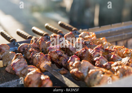 Barbecue sul grill closeup. Lo Shashlik fatta di cubetti di carne su spiedini durante la cottura sul mangal su carbone all'esterno. Foto Stock