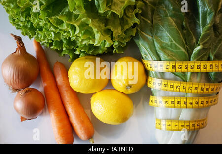 Sana e verdure biologiche e limone con metro a nastro piatto, laici. Mangiare sano, dieta e detox dopo il concetto di vacanza Foto Stock