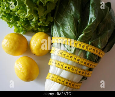 Naturali freschi ingredienti per insalata, limone, inverno lattuga e bietole con metro a nastro. Mangiare sano concetto Foto Stock