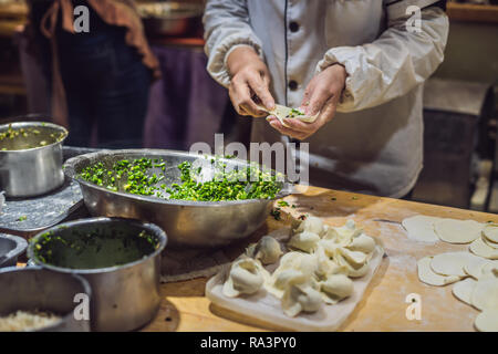 Lo chef cinese rendendo gnocchi di patate in cucina Foto Stock