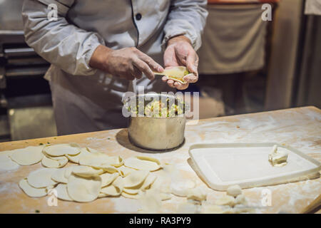 Lo chef cinese rendendo gnocchi di patate in cucina Foto Stock