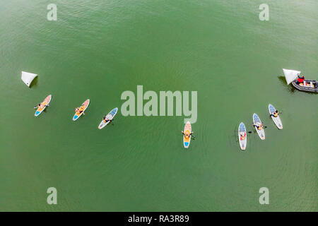 Uomini forti galleggiante su un SUP Board in una bellissima baia in una giornata di sole. Vista aerea di uomini attraversa la baia con il paddleboard. Sport acquatici, competizioni Foto Stock