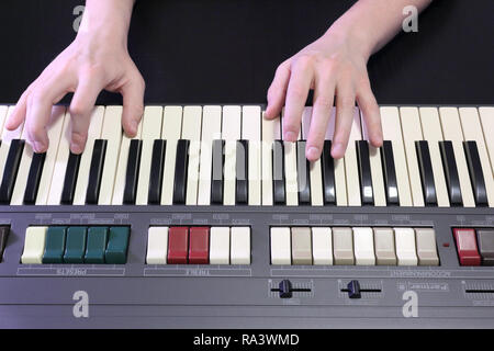 Una mano destra giocando a B (SI) principali corda su un vecchio nero pianoforte con ingiallito Tasti rotti, premendo il tasto B (SI), D# sharp (RE#), F# sharp (FA#) note Foto Stock