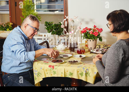 Felice gioiosa coppia senior giocando a carte o godendosi un snack a casa. Foto Stock