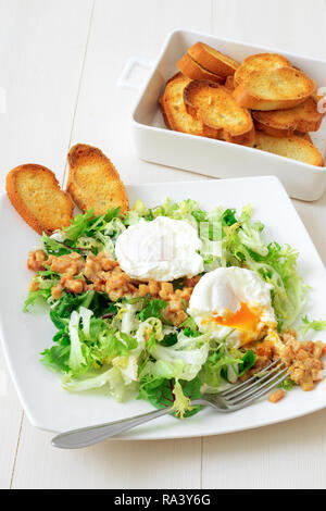 Classica insalata francese, grande insalata Lyonnaise. Il piatto con il verde delle foglie di lattuga, Digione la salsa di senape con pezzi di pancetta fritta e grigliate di pane francese, Foto Stock