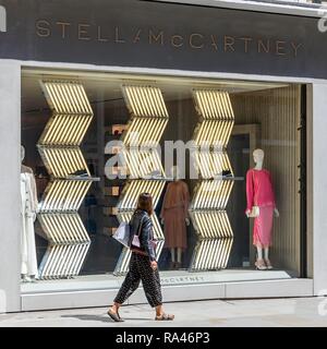 Passante nella parte anteriore del negozio finestra, fashion shop Stella Mc Cartney, London, Regno Unito Foto Stock