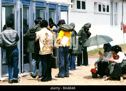 1975 - rifugiati vietnamiti attendere prima di utilizzare i telefoni a una temporanea struttura di alloggiamento. Foto Stock