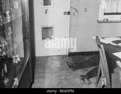 Il ventesimo secolo in bianco e nero di medicina legale foto di scena del crimine che mostra macchie di sangue e il cadavere di assassinato uomo disteso sul terreno all'interno di casa Foto Stock