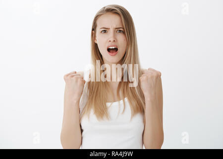 Studio shot di donna realizzare ha perso essere rimasto scioccato e devestated come in piedi con rinserrata pugni, sperando per la vittoria alla ricerca disperata in telecamera con bocca aperta dalla sorpresa e la tristezza Foto Stock