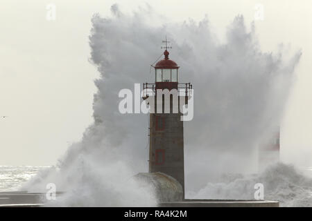 Grande retroilluminato onde tempestose oltre il vecchio faro Foto Stock