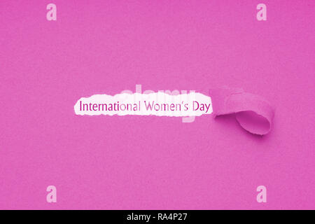 International womens day è celebrata il 8 marzo - testo rivelato dal foro strappata in rosa sfondo della carta Foto Stock