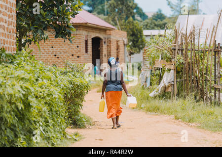 Donna che trasporta l'acqua a Entebbe, Uganda Foto Stock