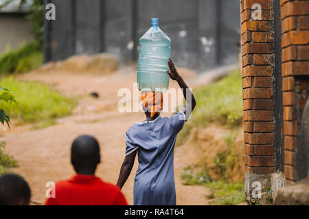 Donna che trasporta l'acqua a Entebbe, Uganda Foto Stock