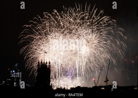 Fuochi d'artificio esplodere vicino al Victoria torre presso il Parlamento e il London Eye nel corso delle celebrazioni per il nuovo anno a Londra il 1 gennaio 2019. Foto Stock