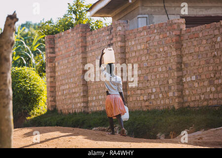 Donna che trasporta l'acqua a Entebbe, Uganda Foto Stock