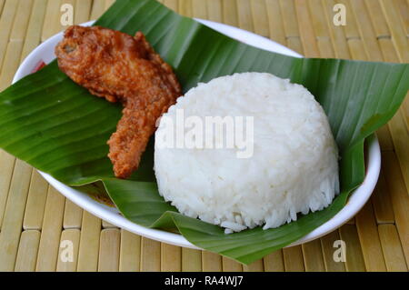 Deep Fried Chicken wing mangiare giovane con riso su fresco banana leaf Foto Stock